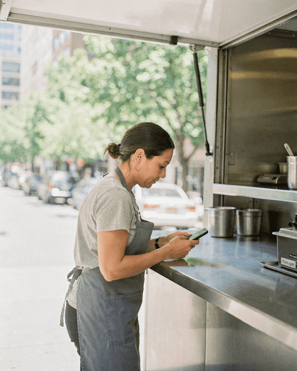 Food truck owner checking her phone at the counter during a quiet moment
